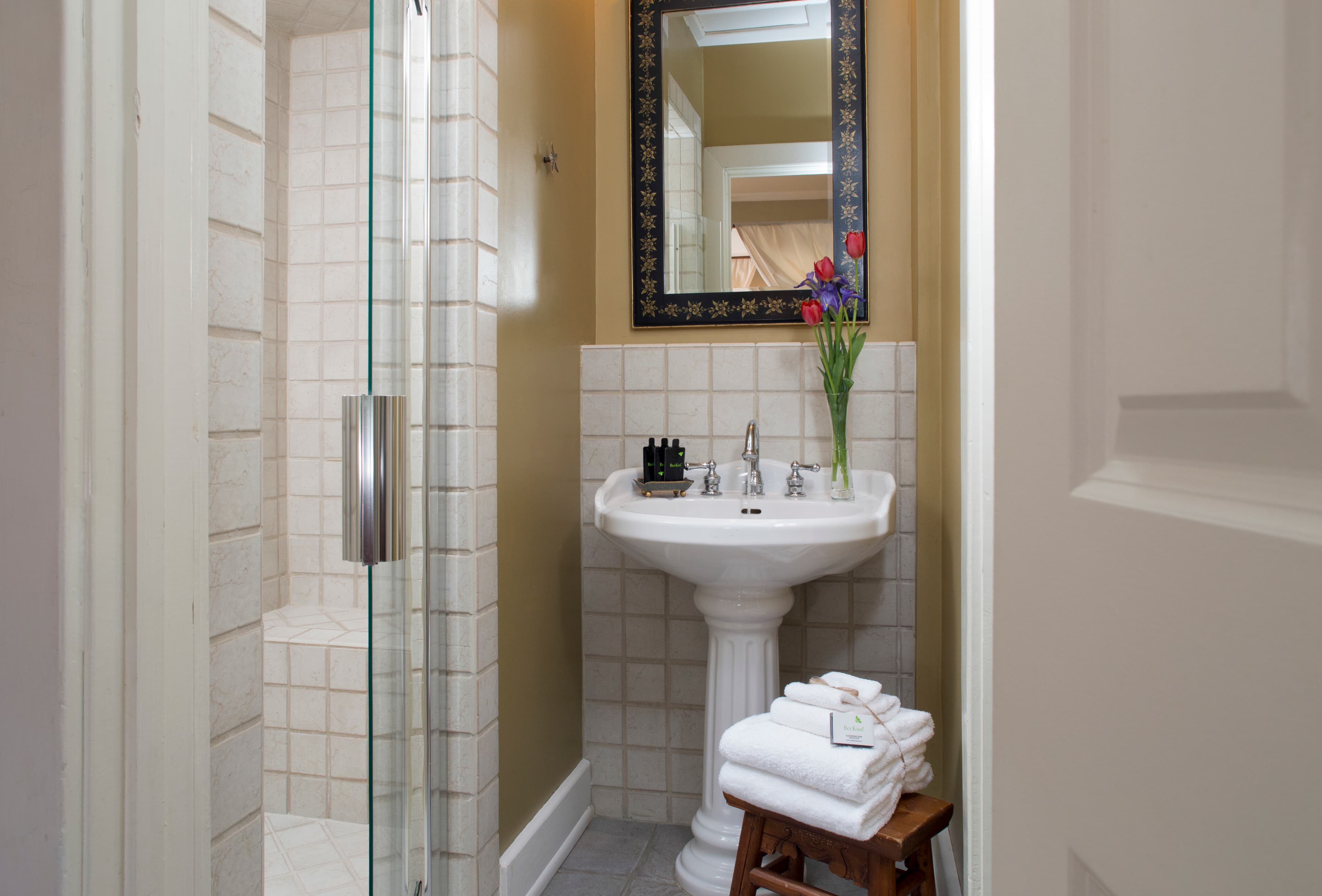 White pedestal sink and tiled shower with glass doors