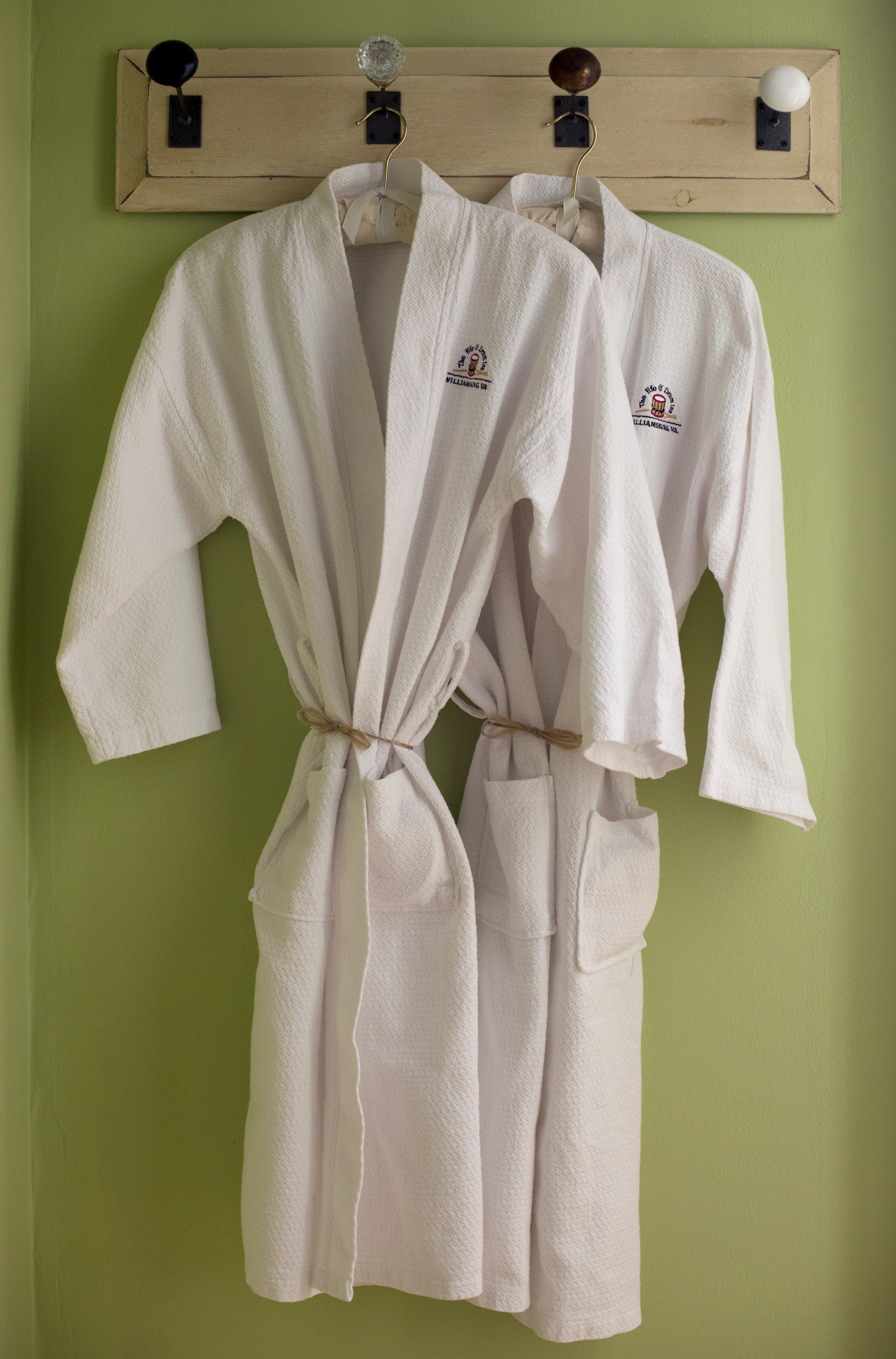 Two plush white robes hanging on decorative wall hooks