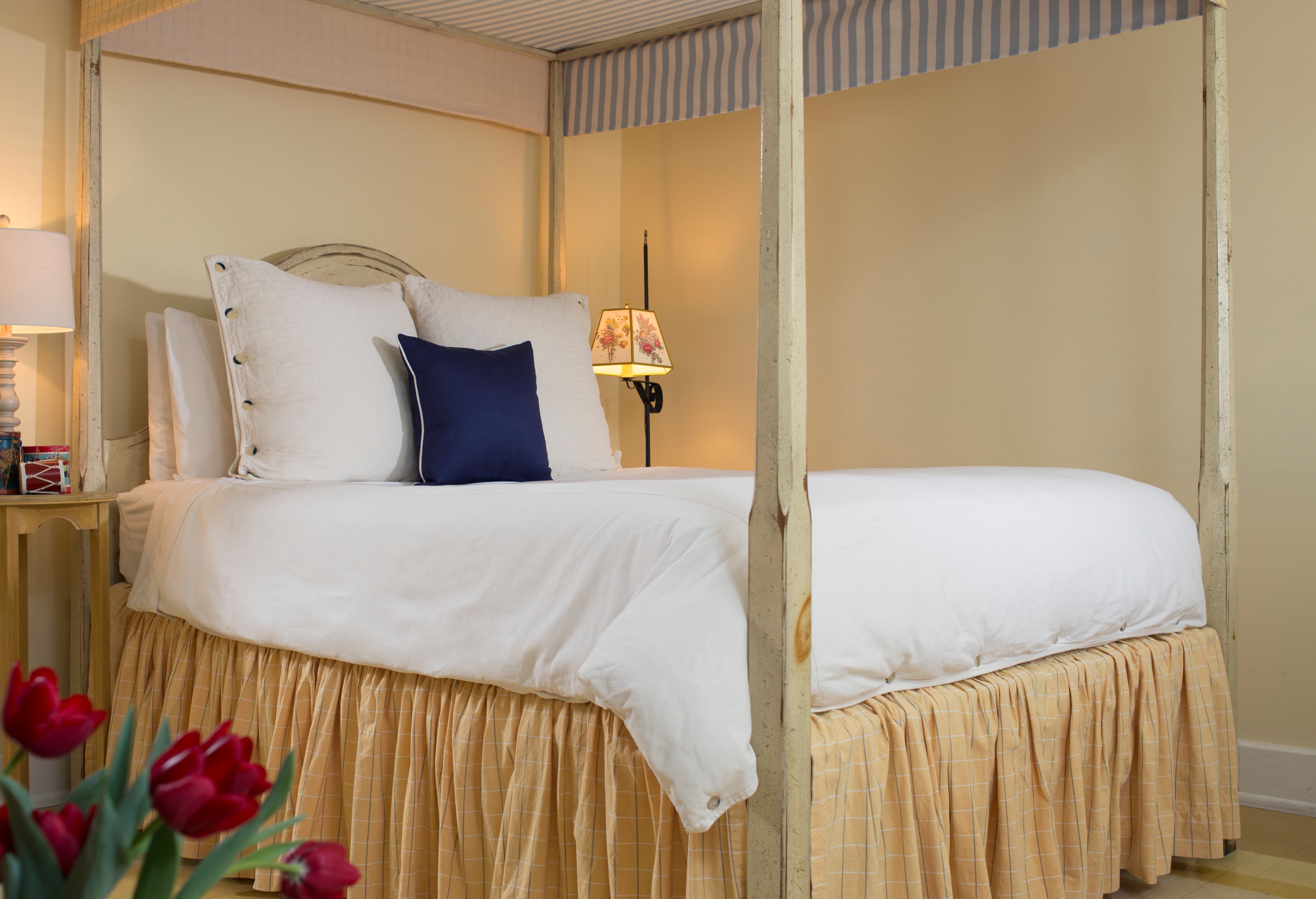 Wooden distressed painted four-poster bed with canopy and long pleated bed skirt