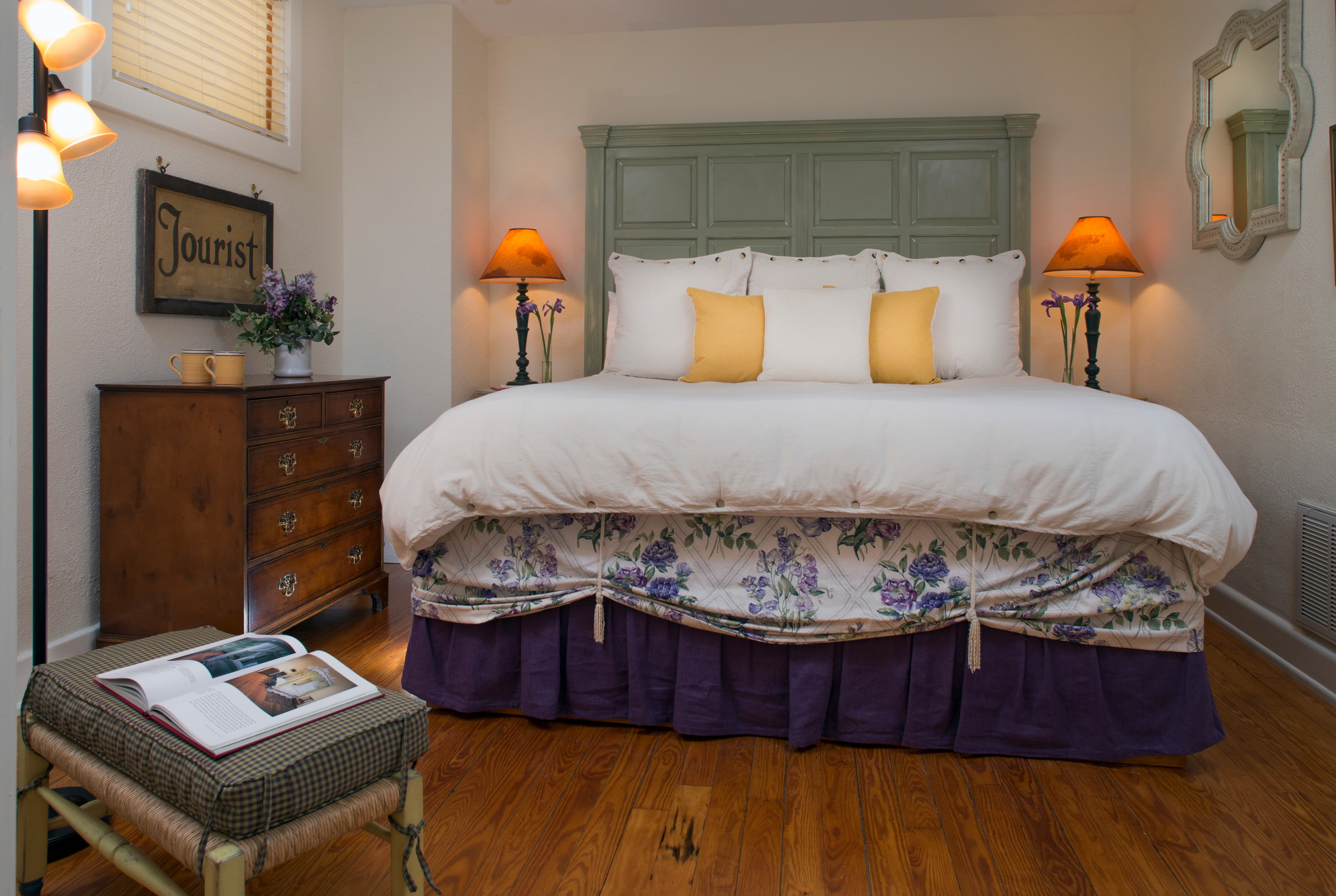 Bed with painted paneled headboard, lofty white comforter and double layered bedskirt